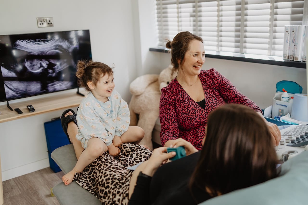 Maria with a parent and her daughter - all smiling - during a private pregnancy scan at Sneak-A-Peek Ultrasound.
