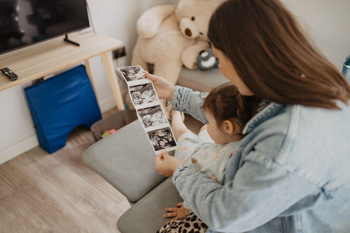 A parent and her daughter looking at pictures of their first NHS pregnancy scan.