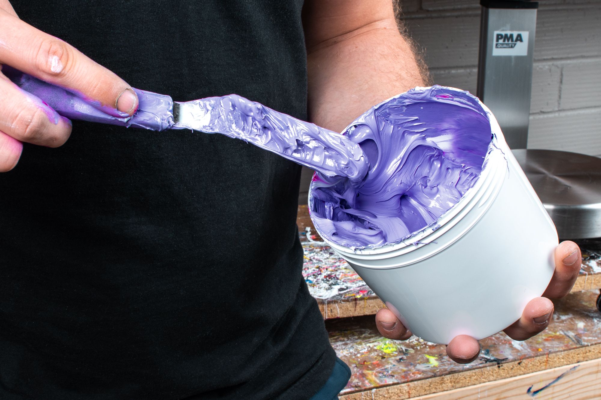 UberPrints production artist mixes a canister full of Very Peri, the Pantone Color of the Year. The dark periwinkle is glazed all on the inside of the canister while he mixes the ink with a mixing spatula.