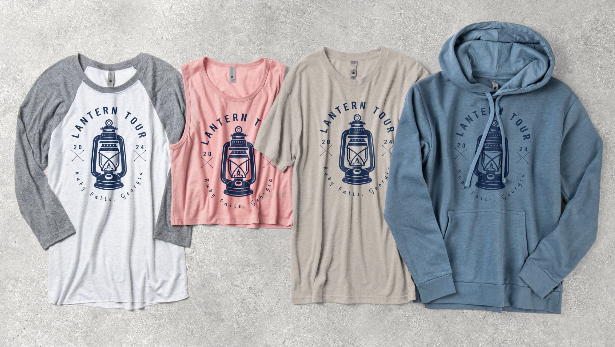 Flatlay of a variety of Next Level products, such as t-shirts and a hoodie, with a custom design on each.