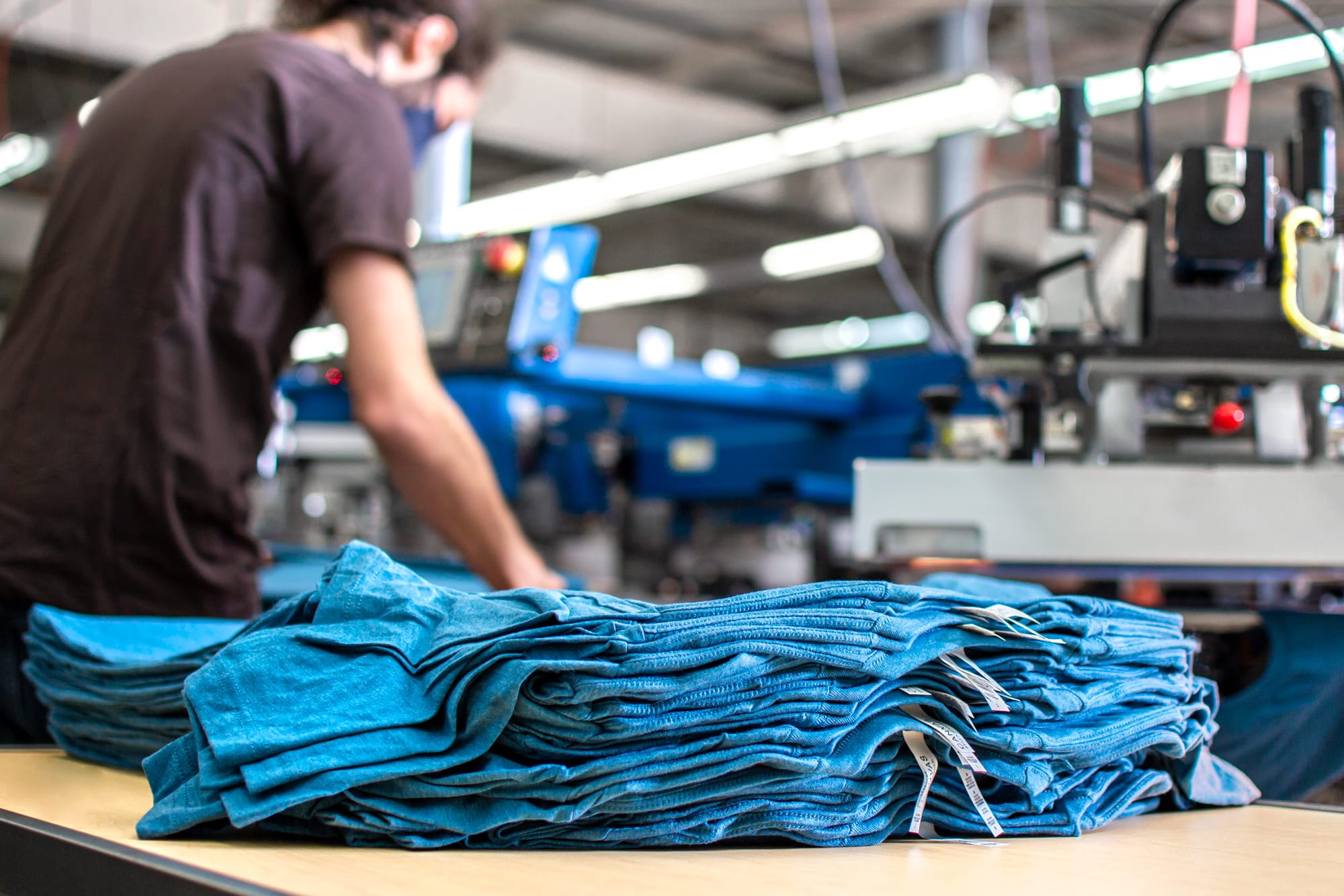 A stack of t-shirts from a bulk order that are getting ready to be screen printed.
