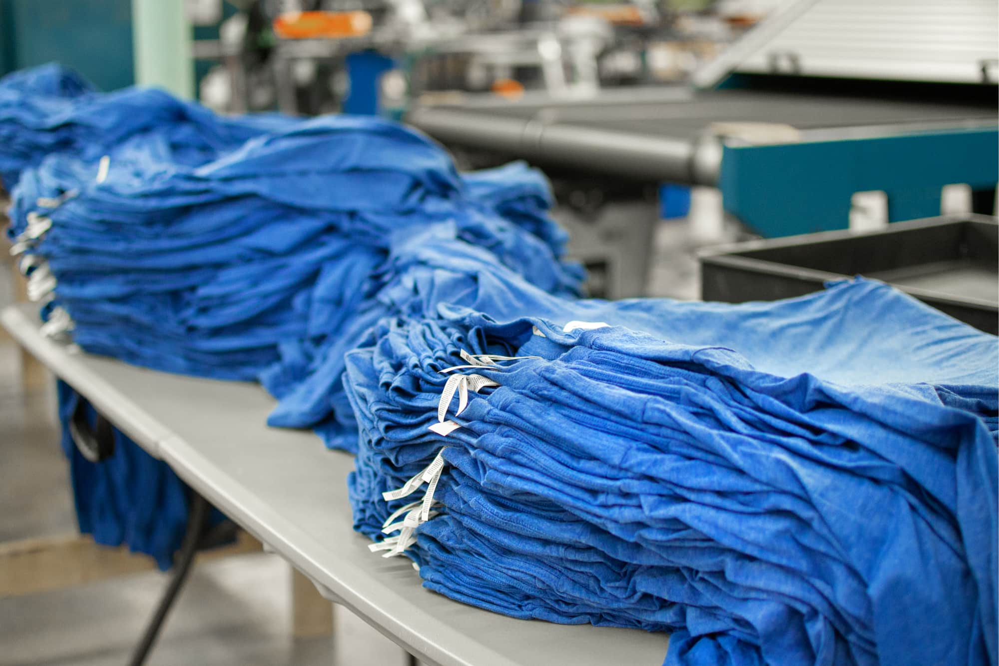 Image of stacks of hundreds of shirts ready to be screen printed