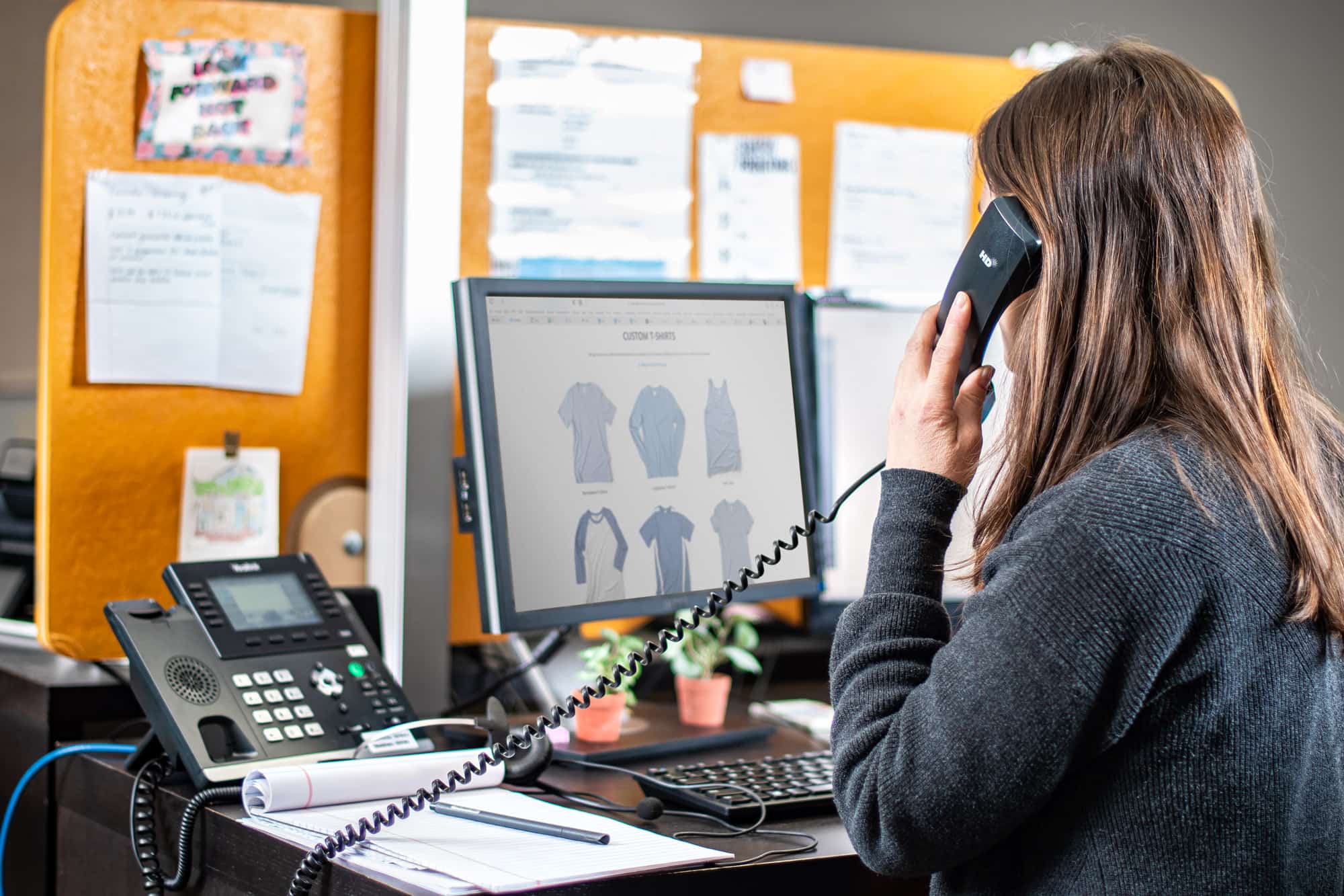 Image of a customer service rep on the phone helping a customer with a t-shirt order.
