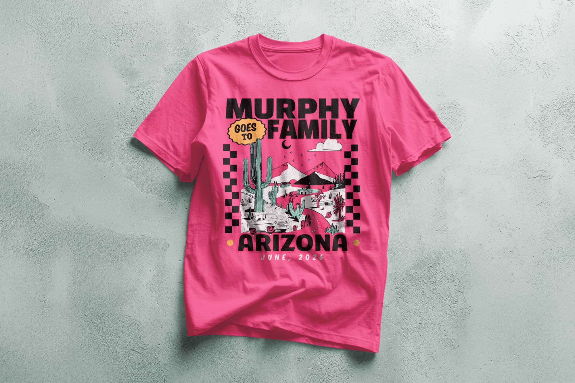 Bright pink T-shirt with "Murphy Family Goes to Arizona, June 2026" in bold text. Design includes desert scene with cacti and mountains, bordered by checkered pattern.