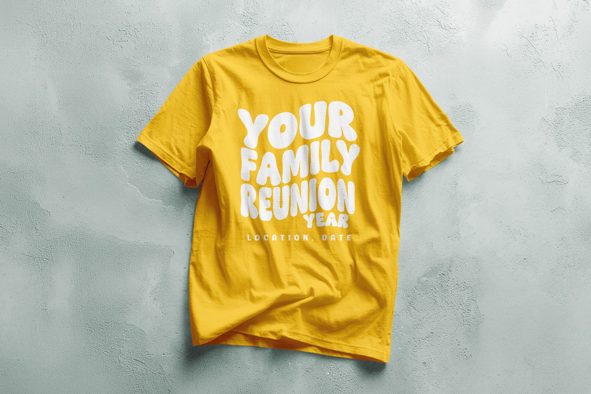 Yellow T-shirt on a textured surface with "Your Family Reunion Year" in bold white and "Location, Date" in smaller text. Bright, cheerful tone.