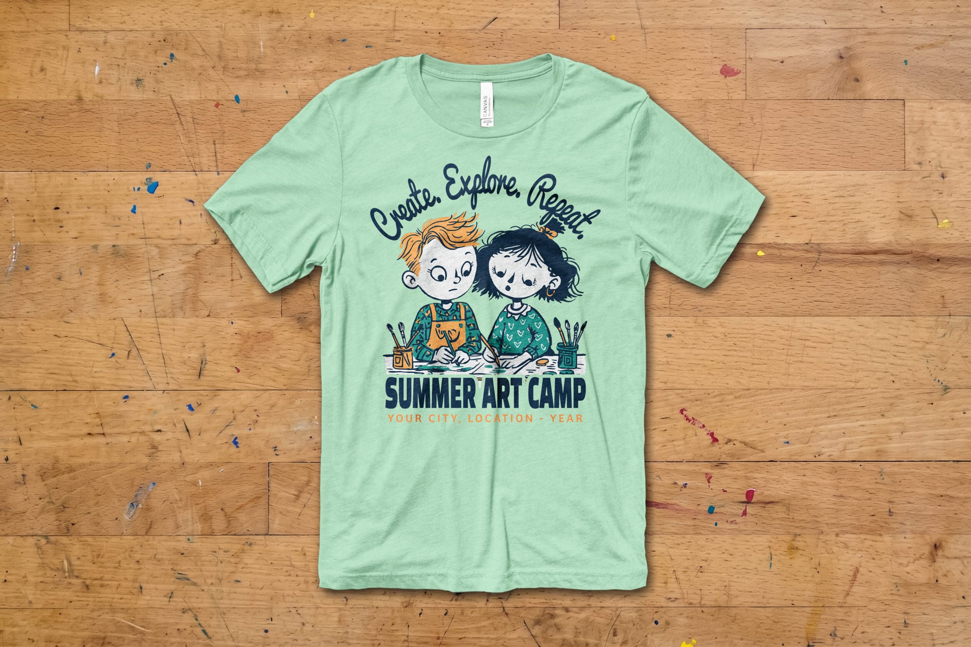 Light green T-shirt on wooden floor, featuring cartoon kids drawing, with text "Create, Explore, Repeat. Summer Art Camp" in playful font.