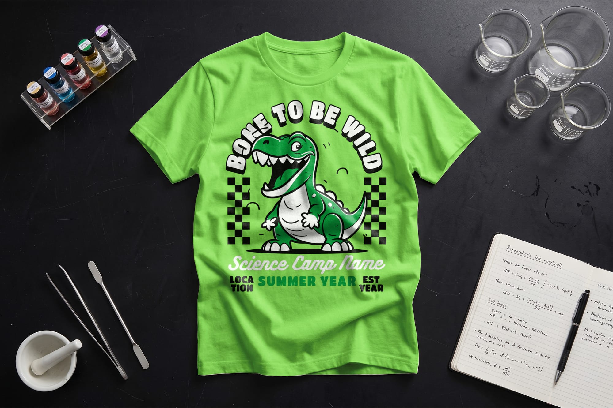 Bright green T-shirt with a cartoon dinosaur and text "Born to Be Wild" in bold. Surrounding items include paint, lab glassware, and a notebook. Playful and scientific theme.