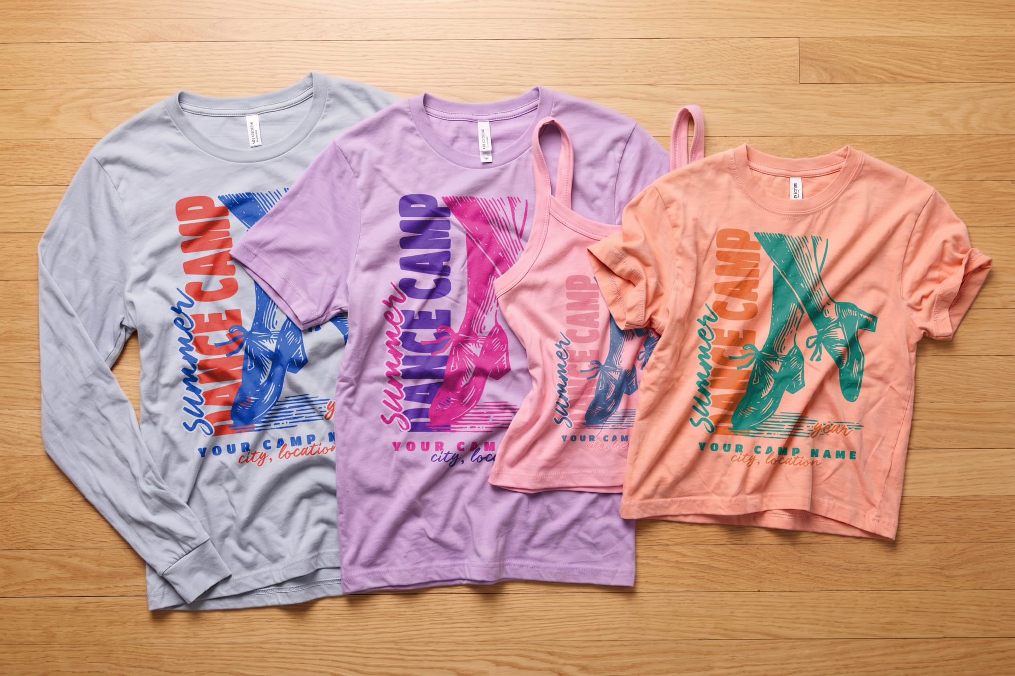 Three summer dance camp shirts and a tank top on wooden floor. Colors: light blue, purple, peach, and pink, each with bold text and ballet shoes graphic.