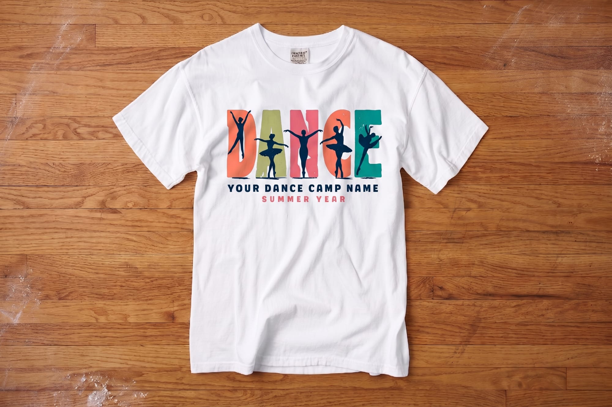 White t-shirt on wooden floor with bold "DANCE" text, featuring dancer silhouettes inside each letter. Below, text reads "Your Dance Camp Name, Summer Year."