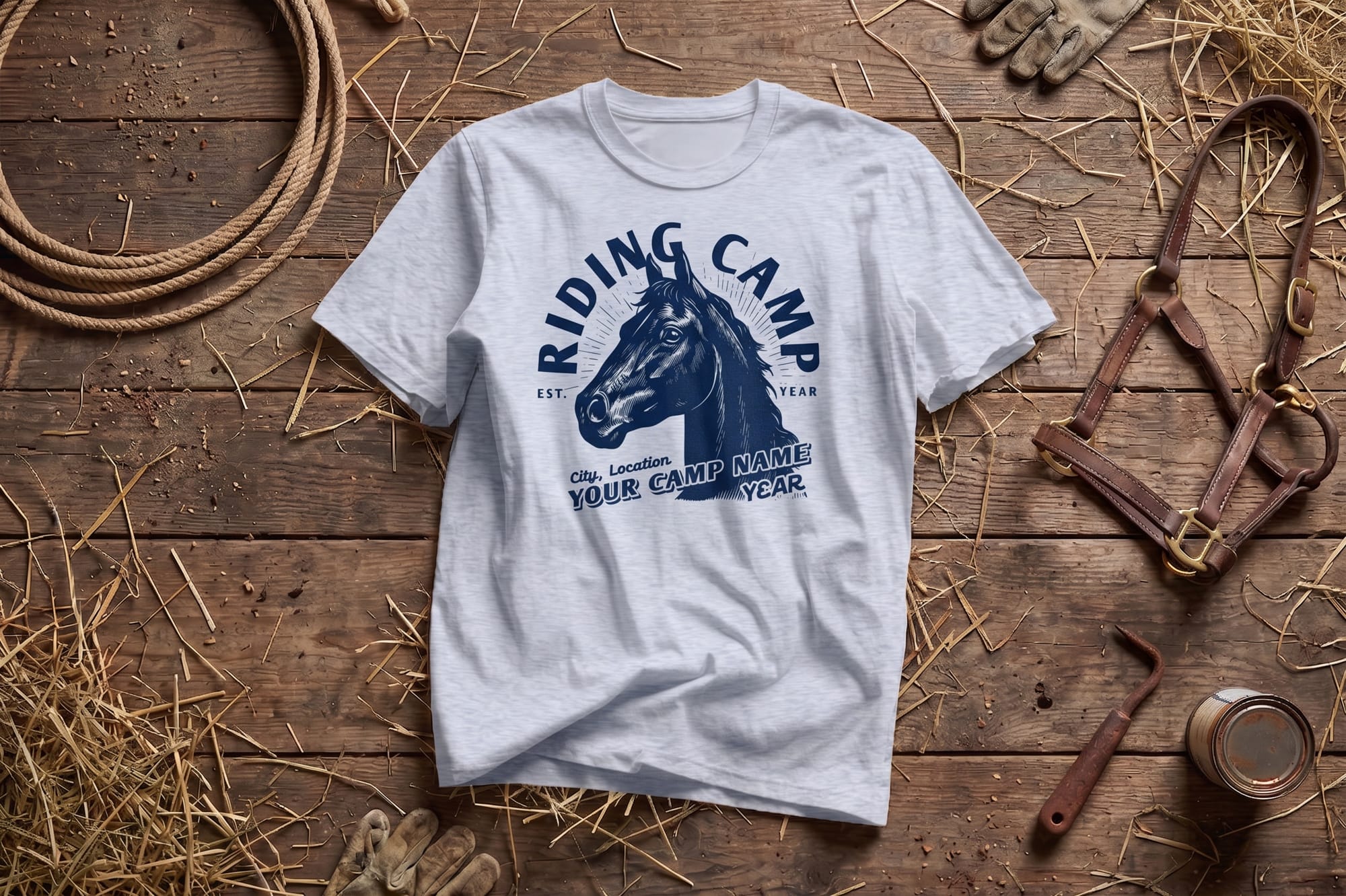 T-shirt with a horse graphic reading "Riding Camp" on a rustic wooden surface. Nearby are a rope, gloves, a leather bridle, and straw, suggesting equestrian activities.