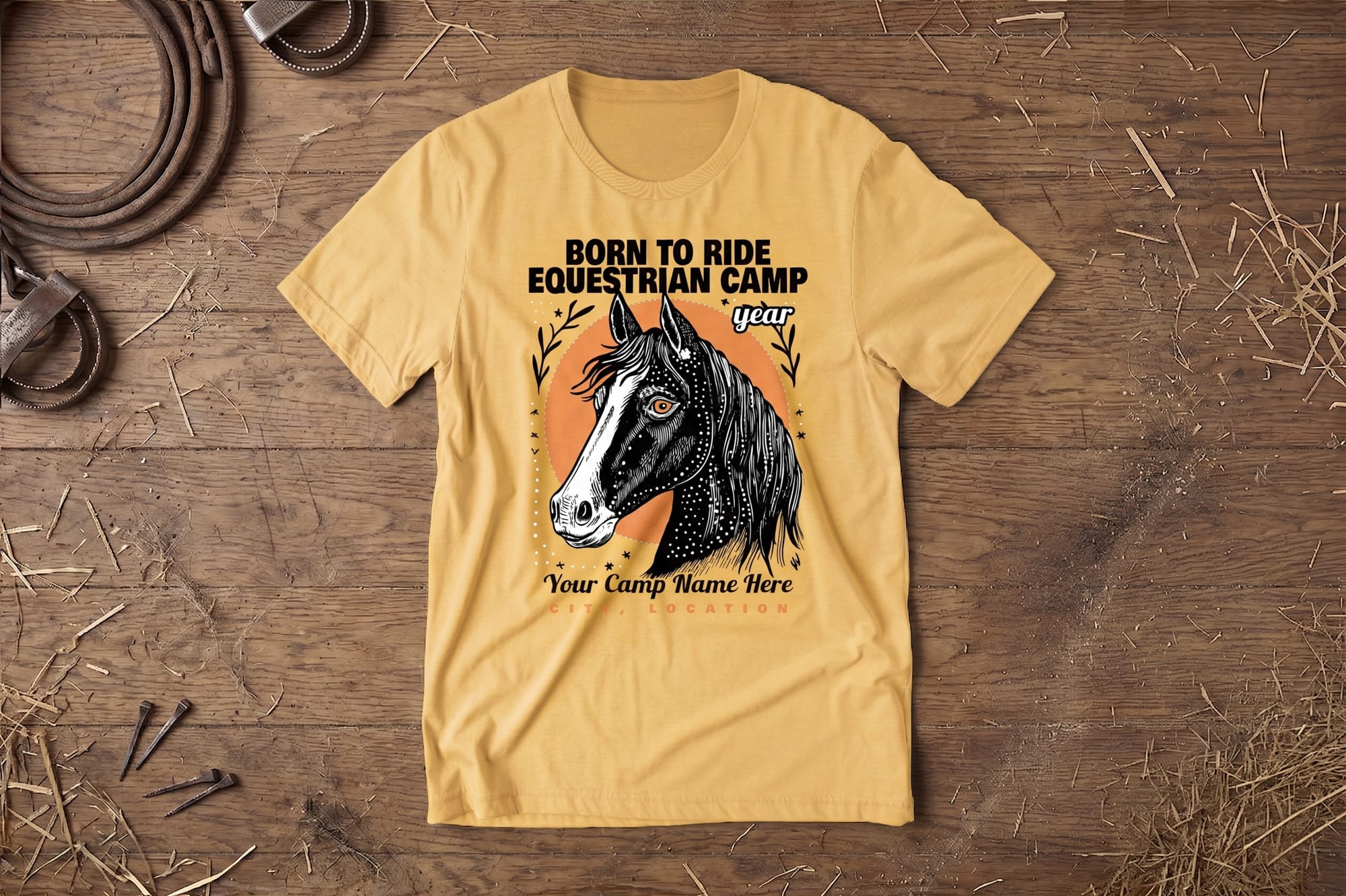 A yellow T-shirt displays a stylized horse head illustration with "Born to Ride Equestrian Camp" text. It lies on a wooden surface with hay and rope, conveying a rustic, adventurous tone.