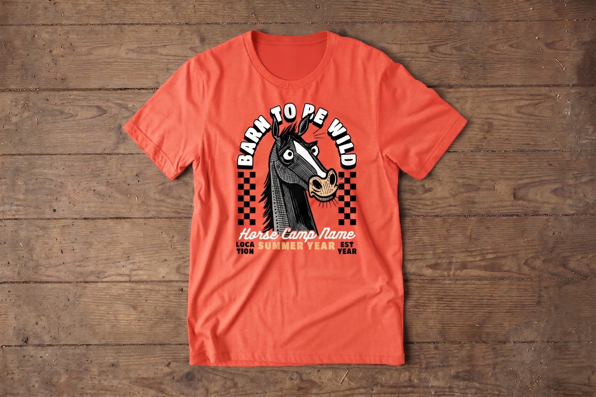 Tangerine colored T-shirt on wood, featuring a cartoon horse illustration with comical eyes, checkered background, and the text "Barn to be Wild" above.