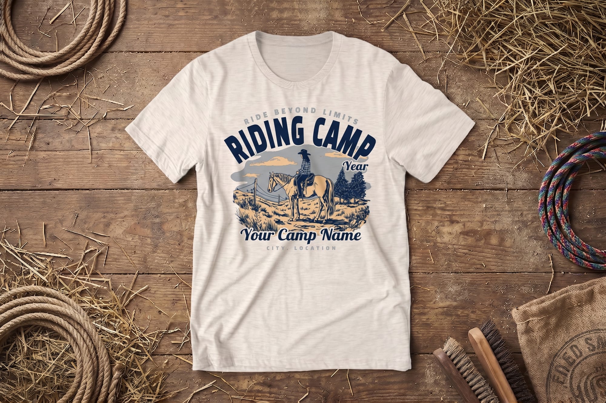 Cream T-shirt on rustic wooden background, featuring a cowboy on horseback with text "Riding Camp." Surrounded by rope, hay, and a brush. Rustic and adventurous mood.