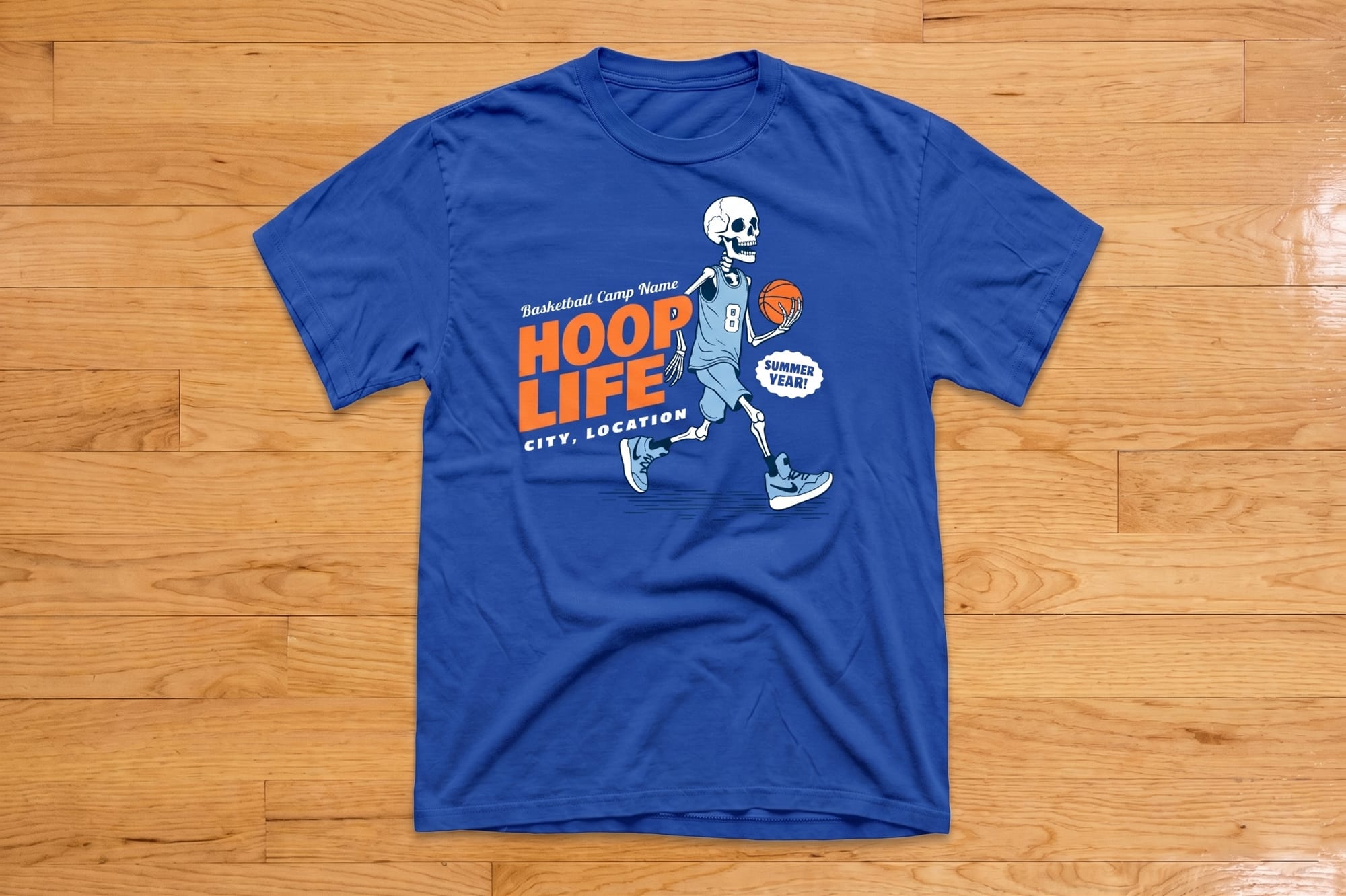 Blue T-shirt with a playful skeleton in a basketball jersey dribbling a basketball. Text reads "Hoop Life" in vibrant orange and white. Fun and sporty vibe.