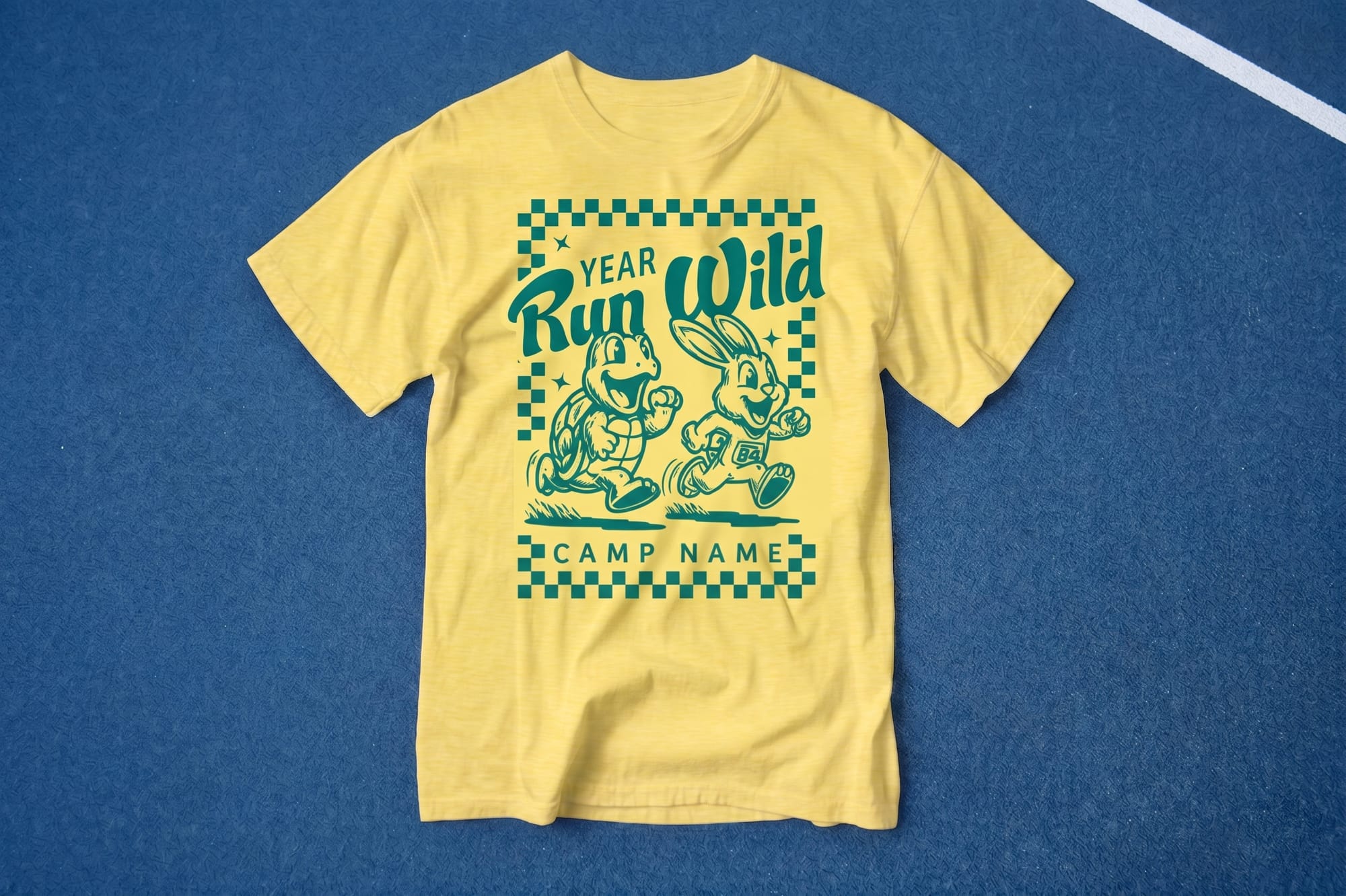 Yellow T-shirt on blue surface featuring a green print of a cheerful tortoise and hare running. Text above reads "Year Run Wild" and below, "Camp Name." Fun and energetic tone.