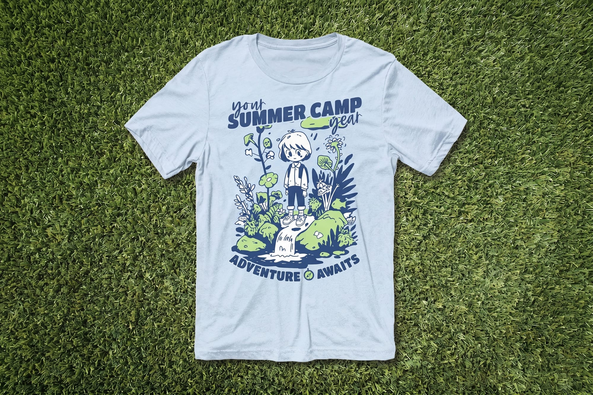 Light blue custom summer camp t-shirt with cartoon nature illustration and 'Adventure Awaits' print, flatlay on grass