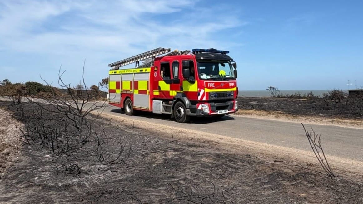 A fire engine amid the burned remains of the heath.