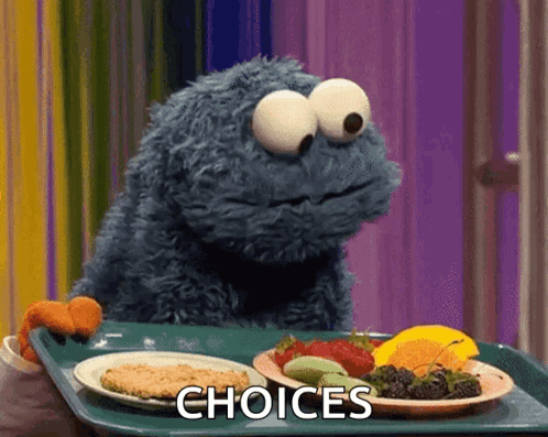 Cookie Monster looking at two plates, trying to choose between a cookie or fruit
