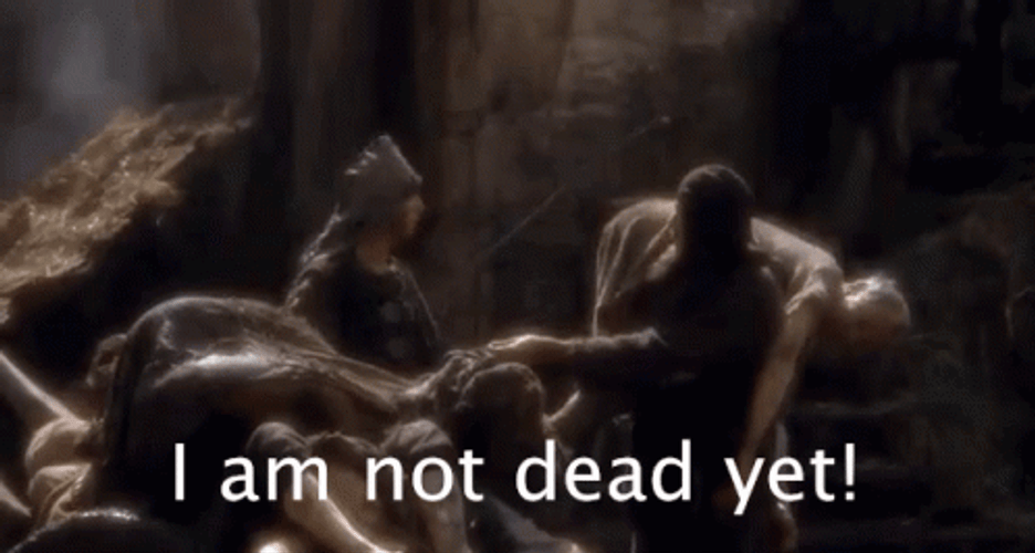A medieval person carrying an old man as if he were dead. The old man says, "I am not dead yet!"