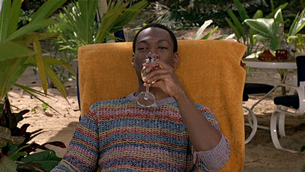 Eddie Murphy in a lounge chair on a beach drinking champagne