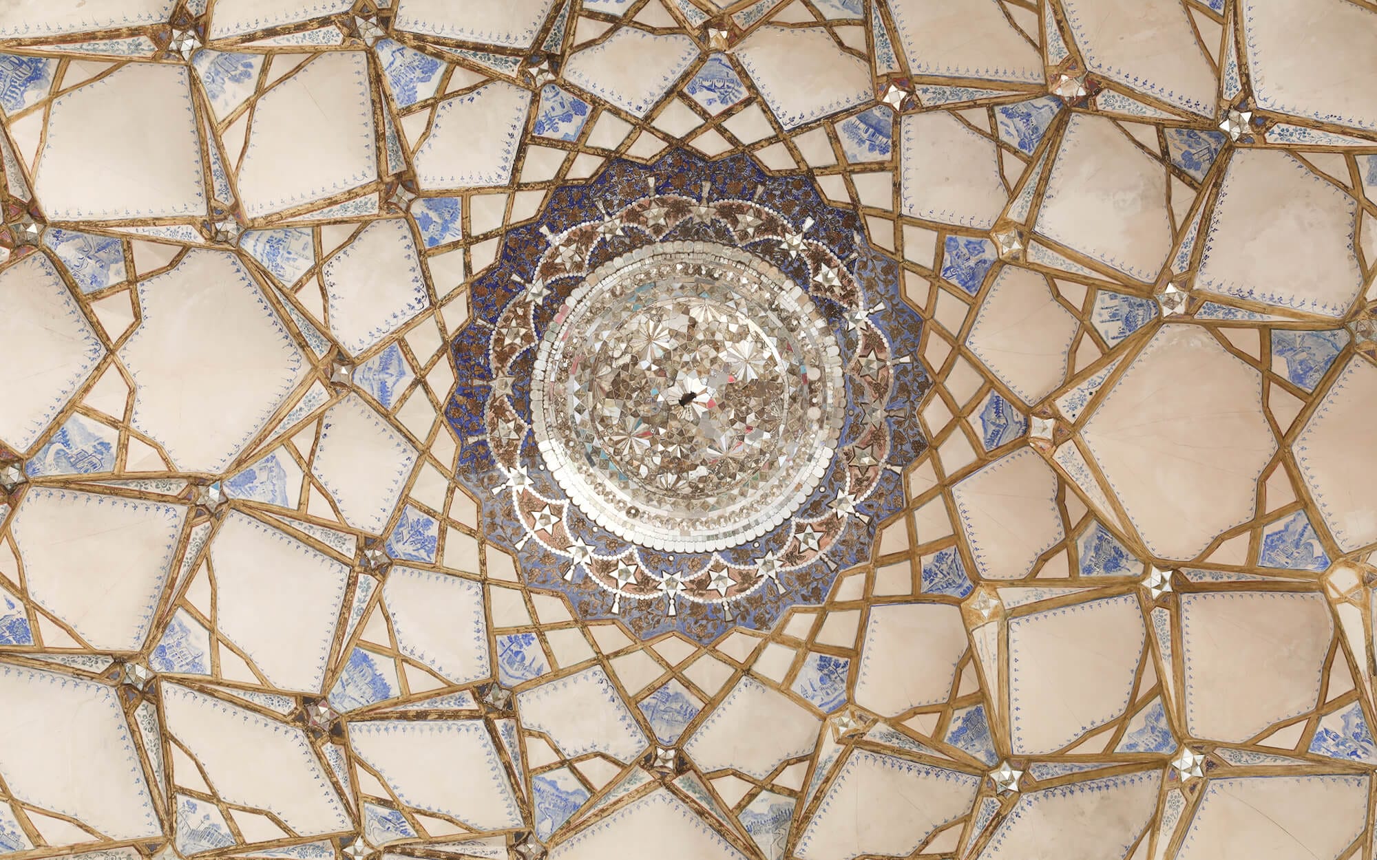Intricate Āina-kāri (mirror work) ceiling of Khaneh Ameri in Kashan, featuring geometric star patterns, gold outlines, and a circular mirrored medallion at the centre.