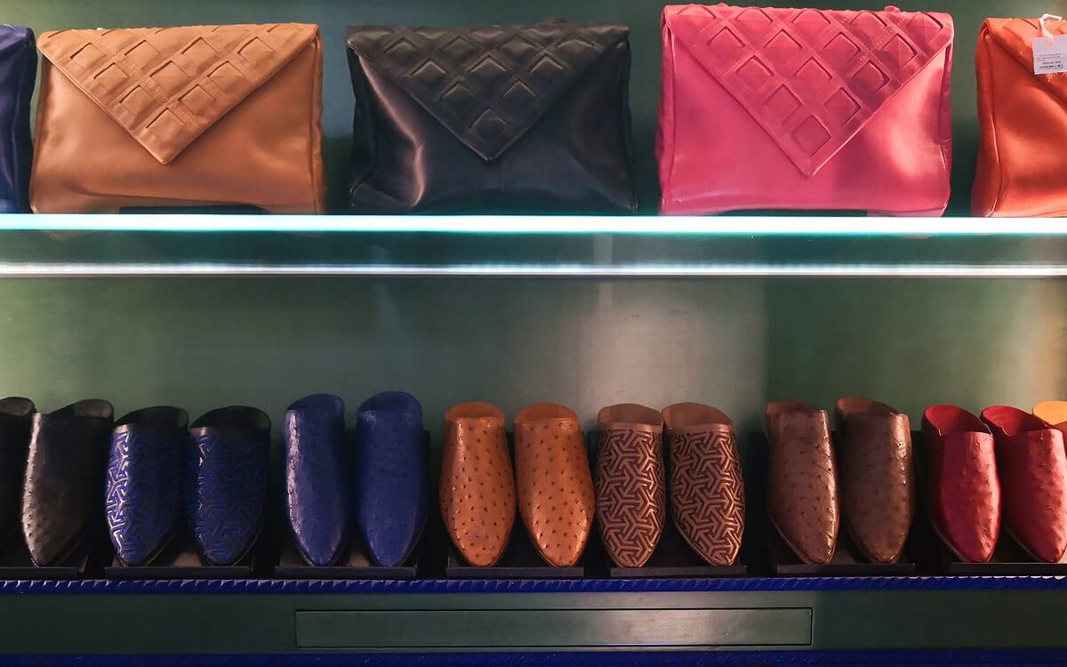 Colorful leather clutches and traditional Moroccan slippers arranged on shelves inside the Jardin Majorelle boutique