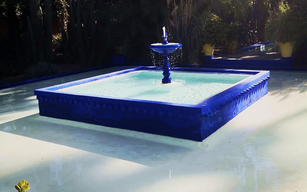 Blue square fountain with flowing water set in a minimalist courtyard at Jardin Majorelle, Marrakech