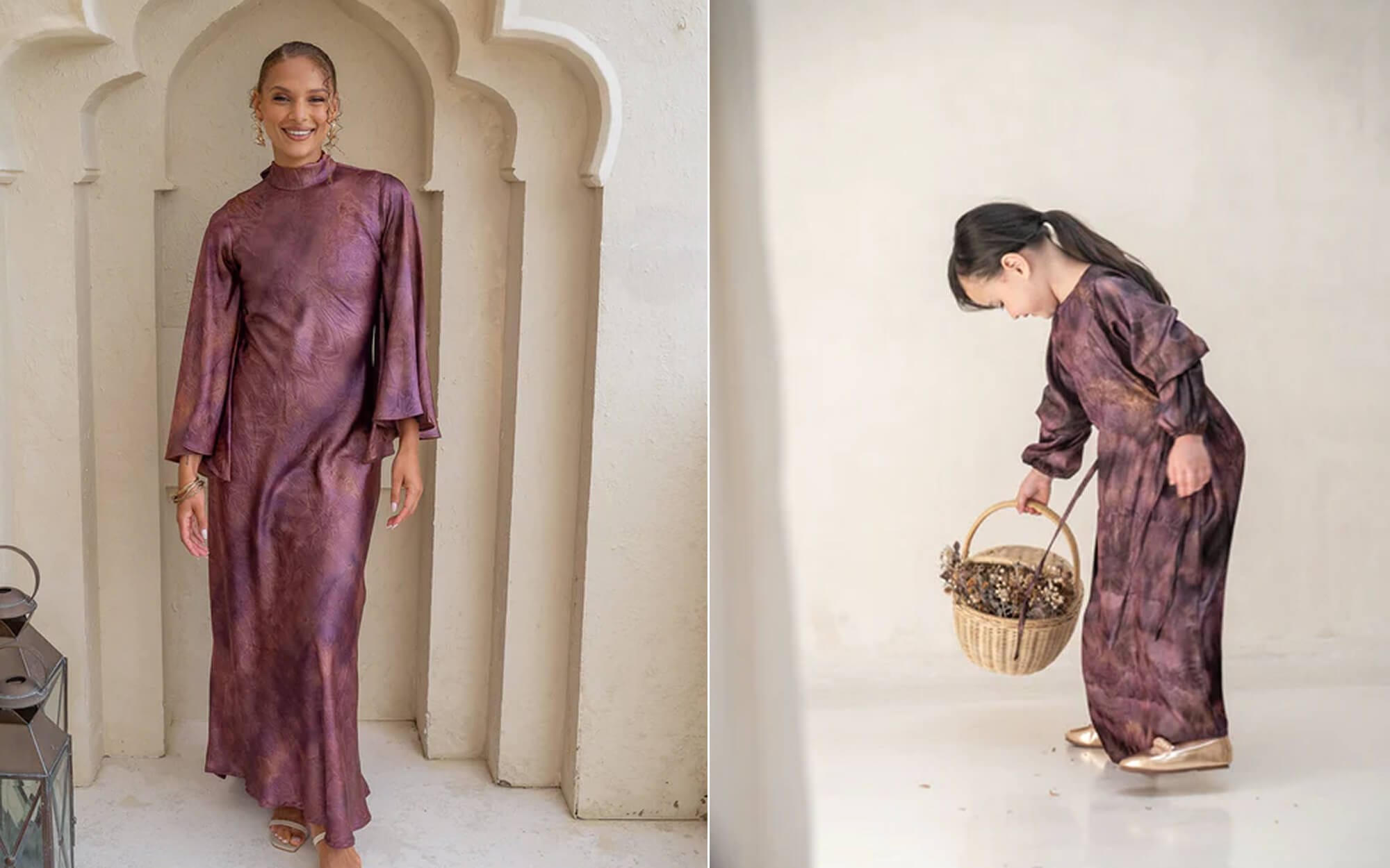 Mother and young daughter in matching modest, soft plum-pink flowing dresses, the child gently bending to hold a small basket in a bright, minimal room.