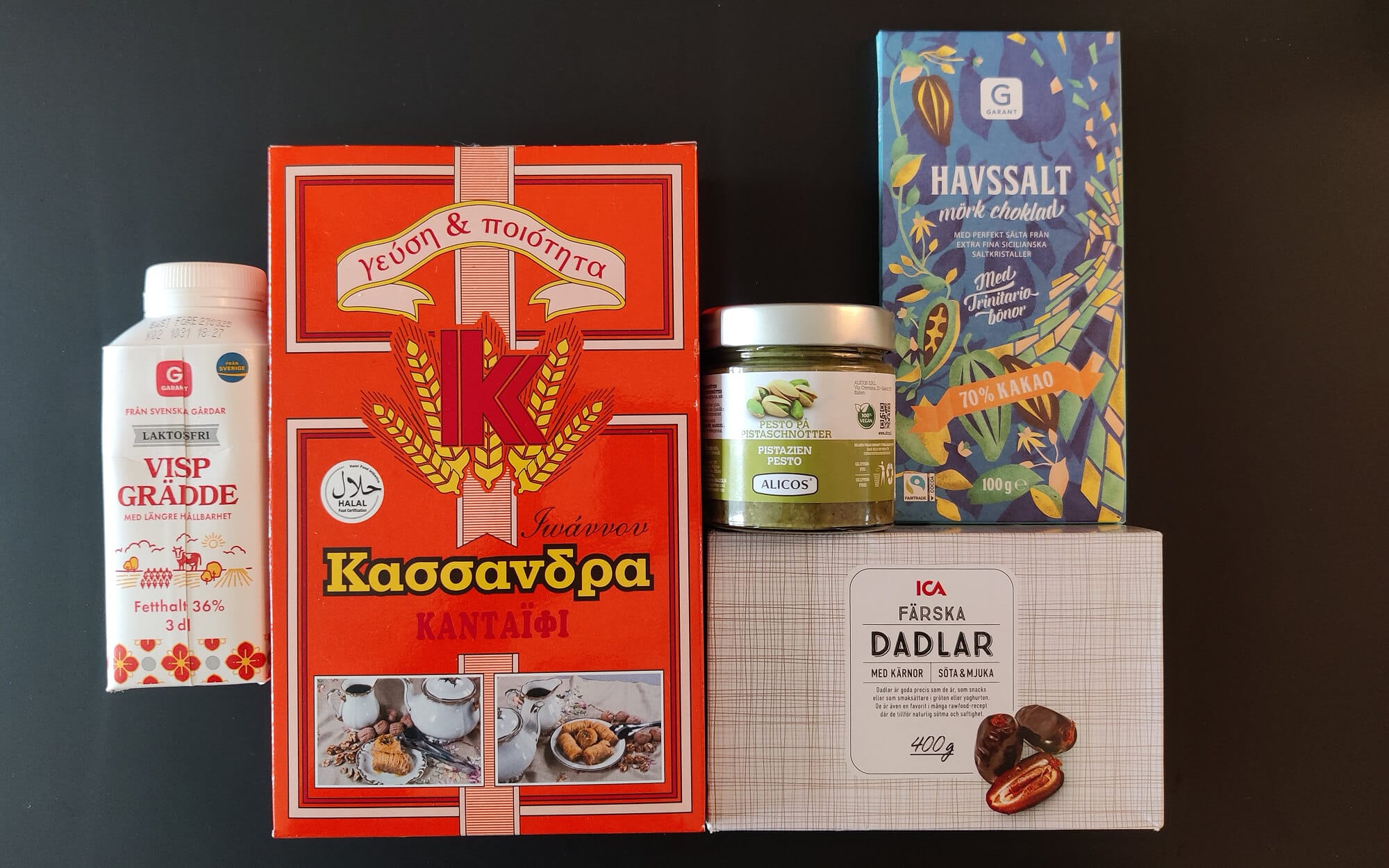 Ingredients laid out on a dark table for healthier Dubai chocolate dates, including fresh dates, dark chocolate, pistachio cream, and flaky Kadaifi pastry.