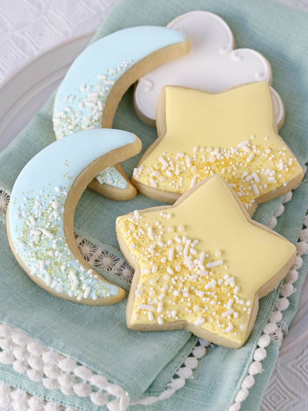 Crescent moon and star ramadan-inspired sugar cookies decorated with pastel icing and sprinkles.