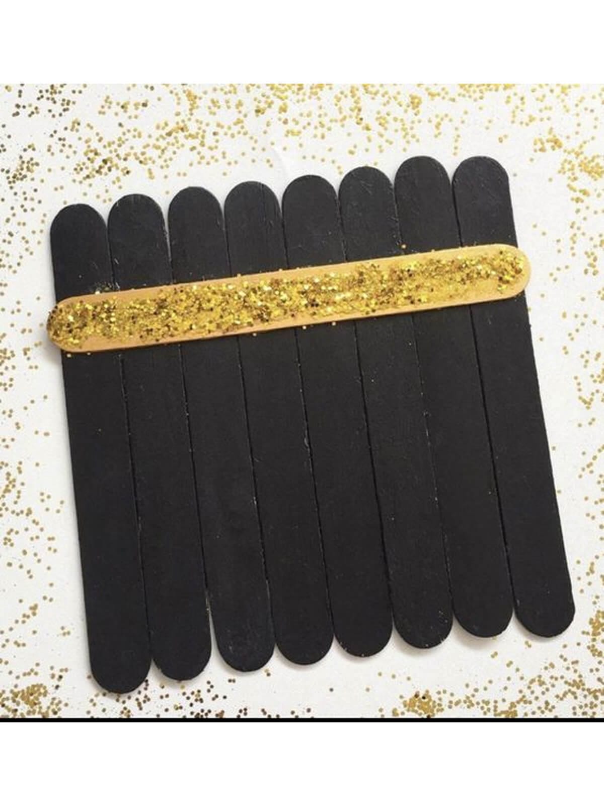 A simple DIY Kaaba made from wooden ice-cream sticks painted black, held together with a single glittering gold stick to mimic the Kiswah band.