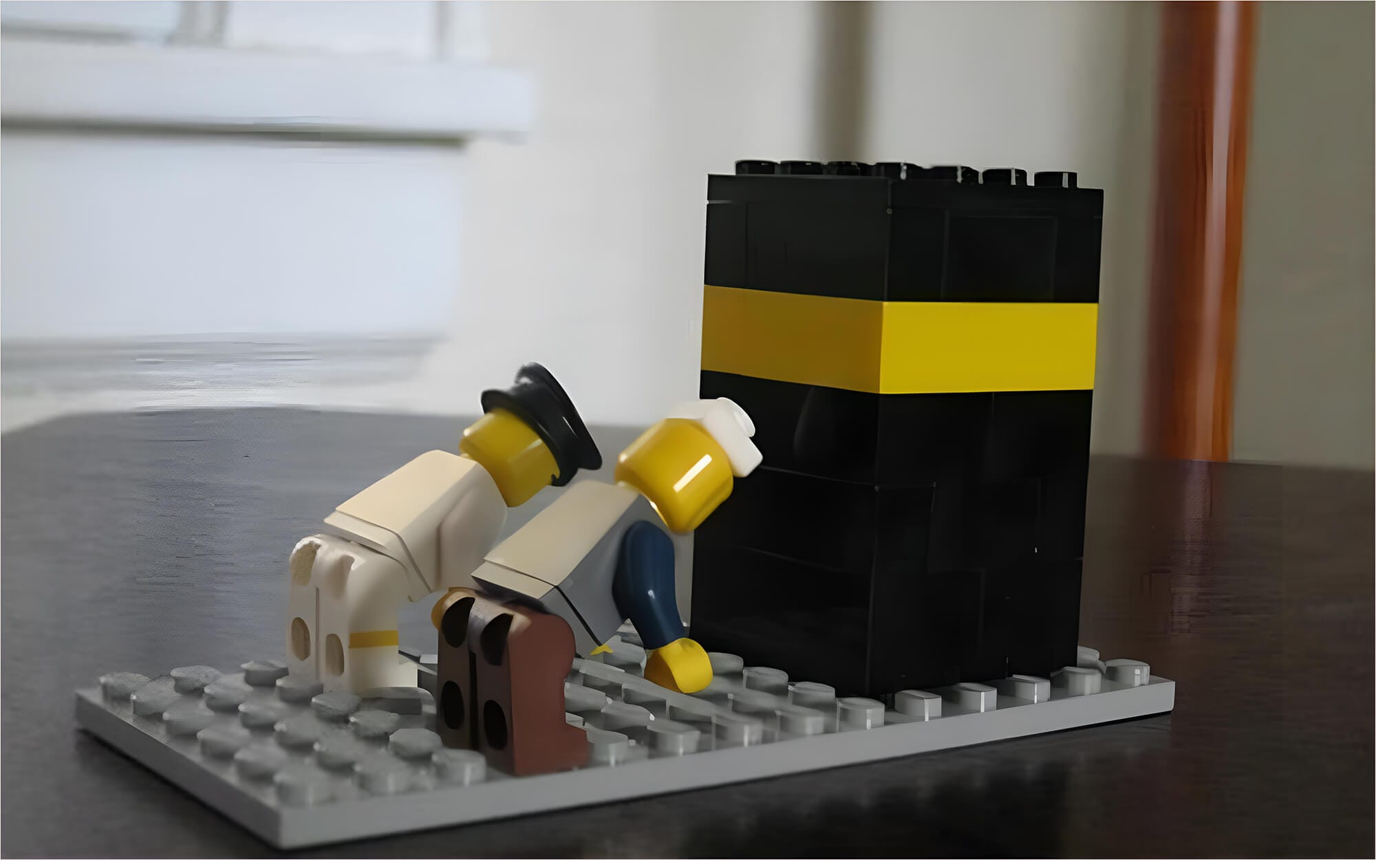 Two Lego figures bowing in front of a black-and-gold Lego Kaaba.