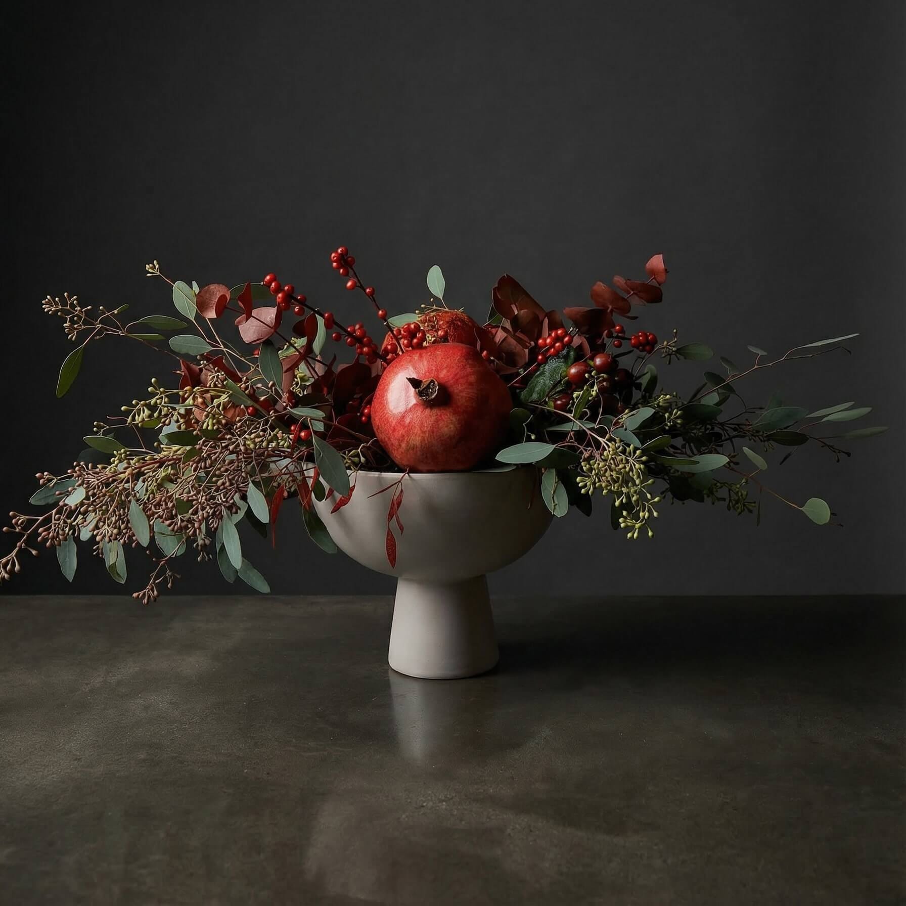 Wild winter centerpiece with pomegranate,eucalyptus, and holly (winterberry)