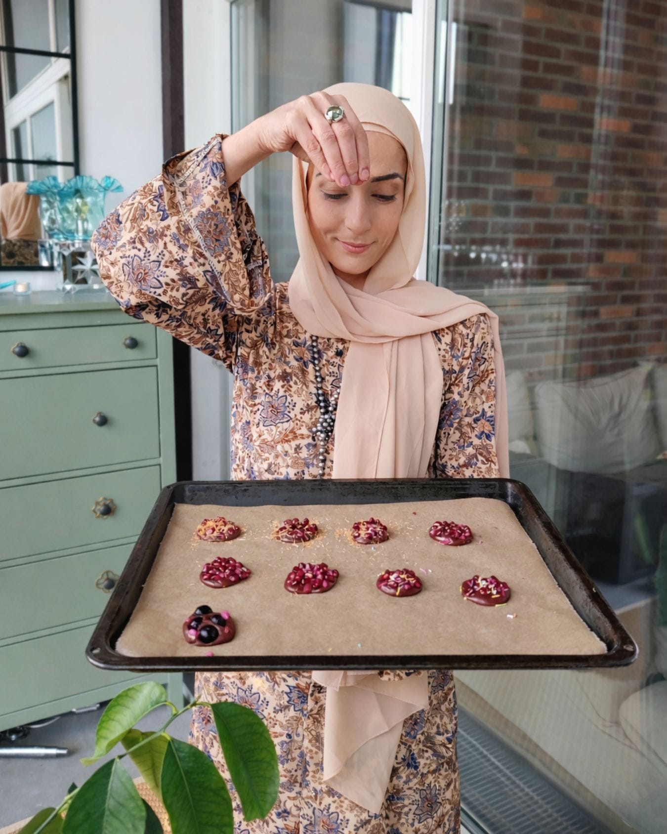 Sprinkling toasted kataifi onto tray for pomegranate chocolate bites