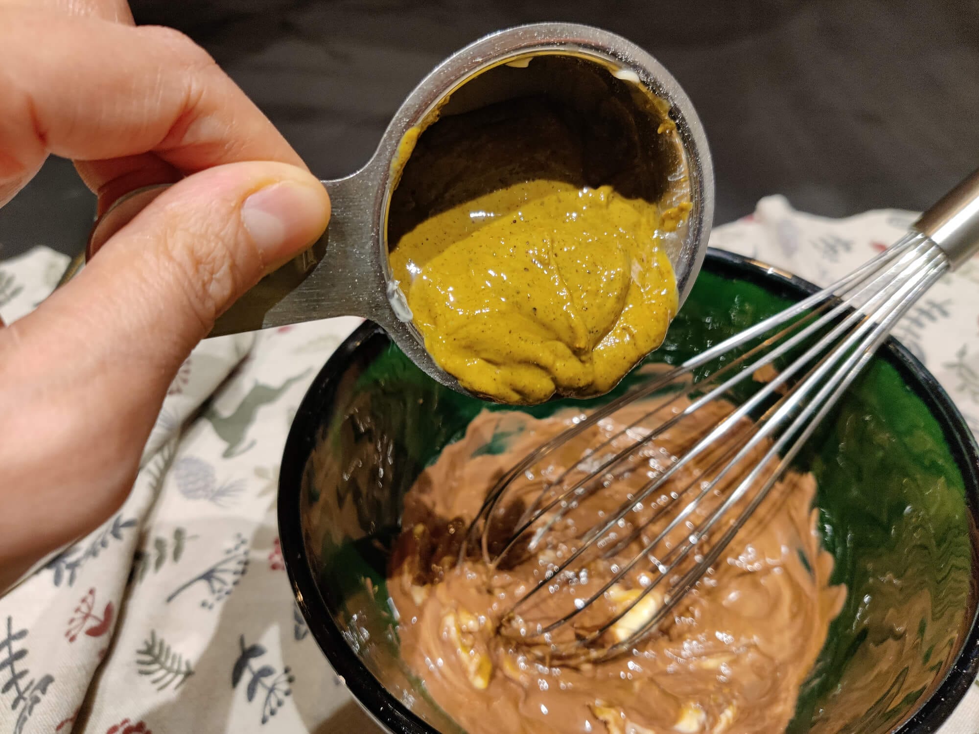 Pistachio cream being added to the melted chocolate and butter mixture for Reindeer Chow