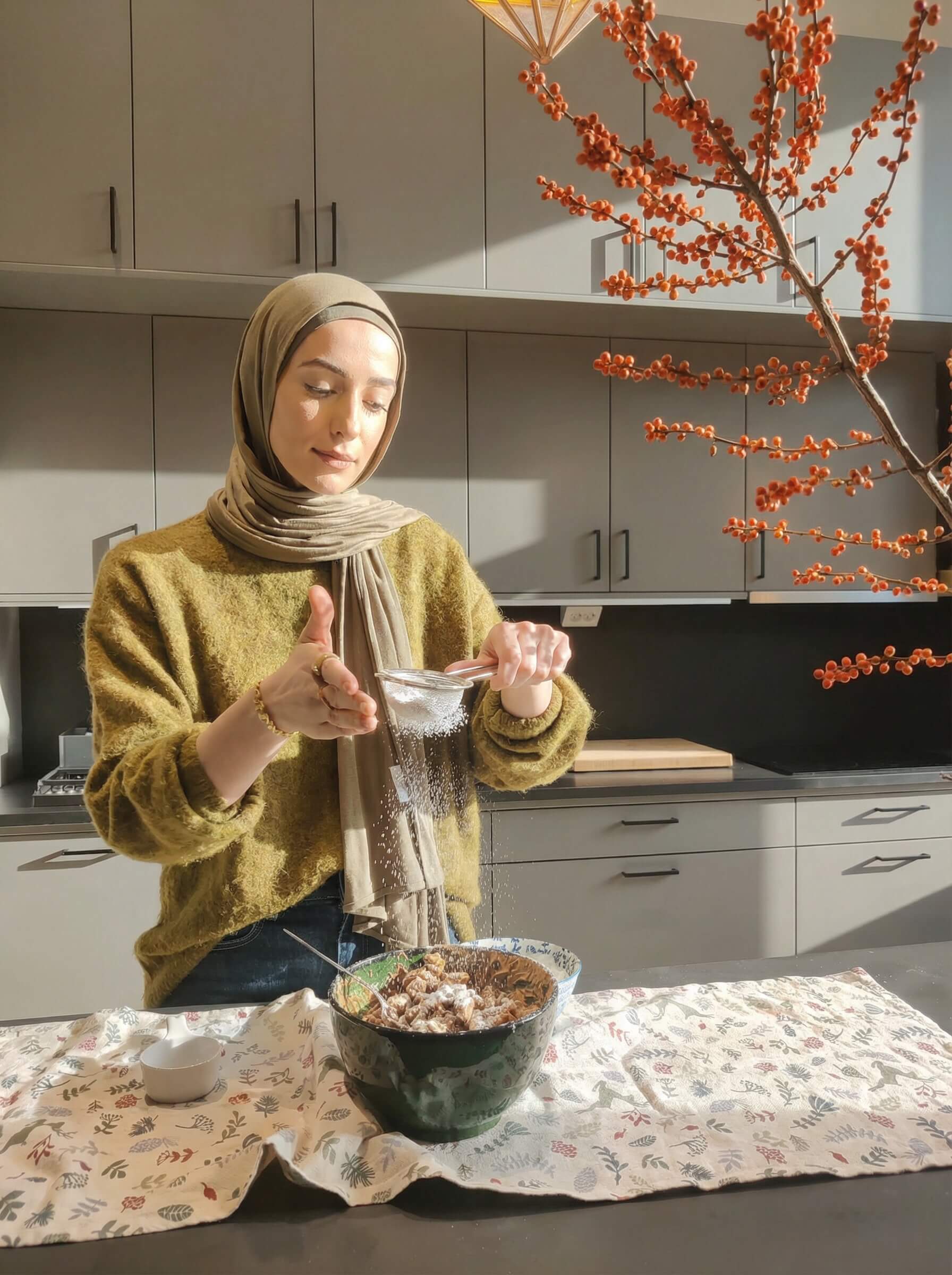 Hijabi Blogger sprinkling icing sugar over pistachio Puppy Chow in a bowl