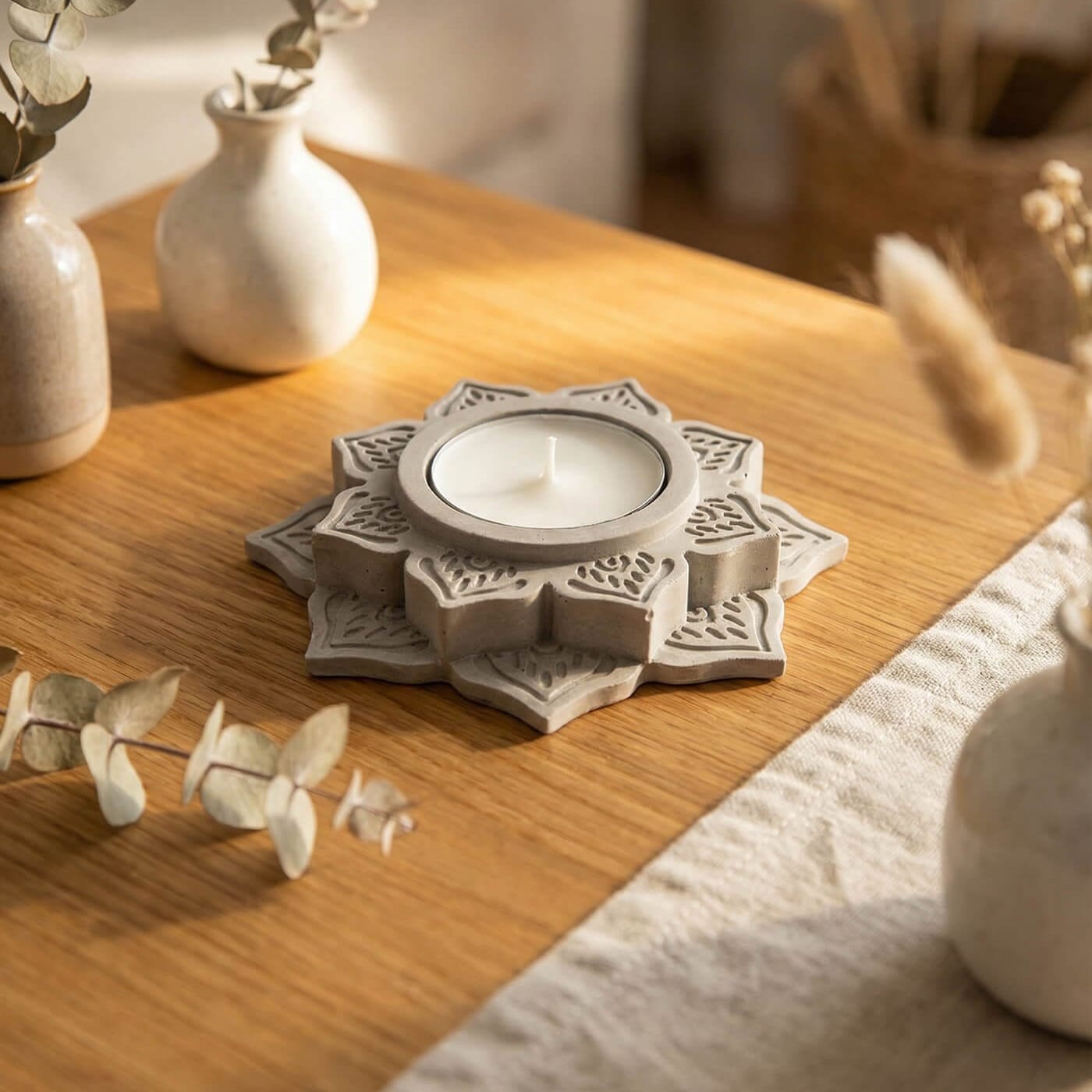 A grey DIY geometric candleholder on a light wood table.