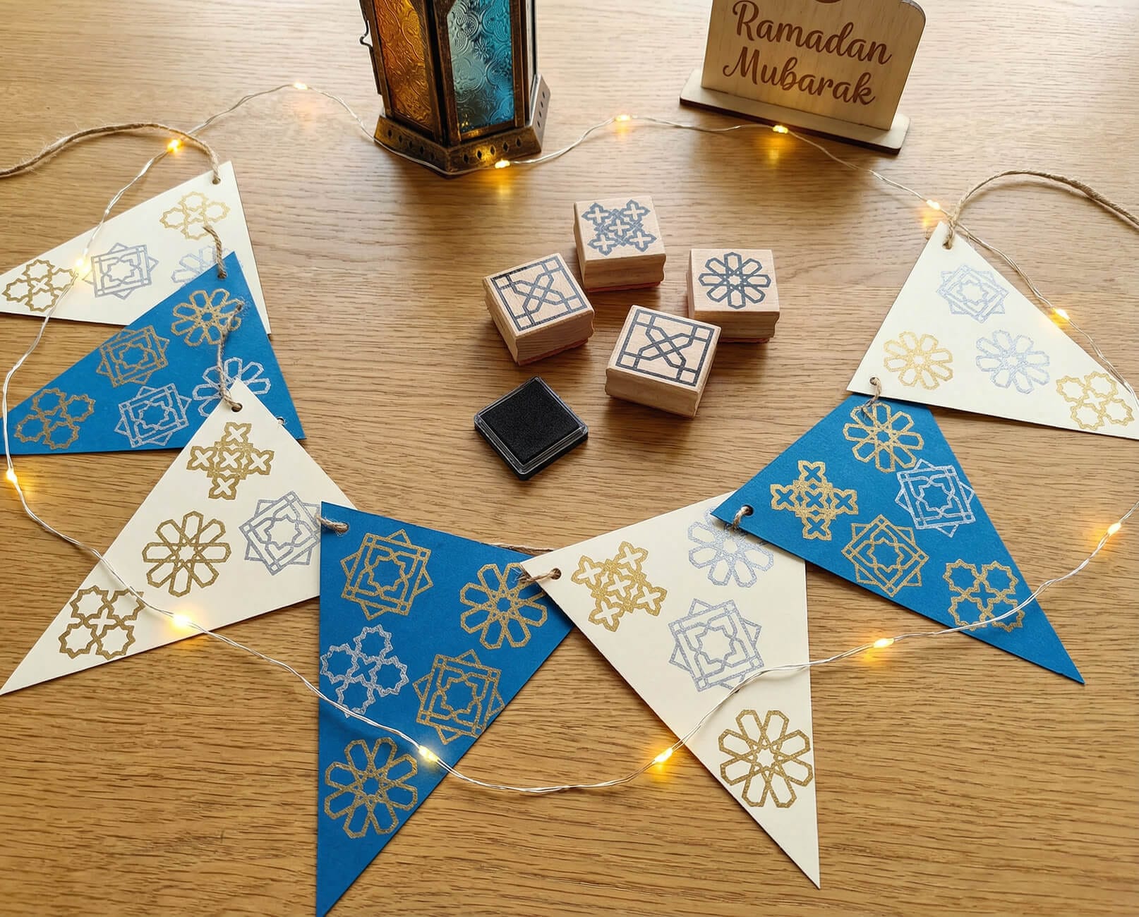 Islamic geometry bunting created with wooden stamps and ink pads, used as a reusable Ramadan decoration at home.