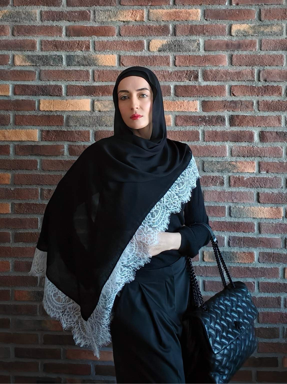 Black modal lace hijab styled with a soft drape over an all-black modest outfit