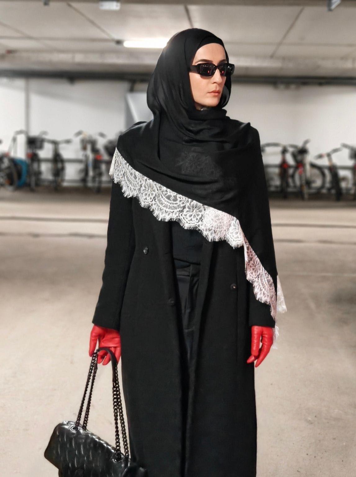 Black lace hijab paired with a tailored coat and red gloves for a winter modest look