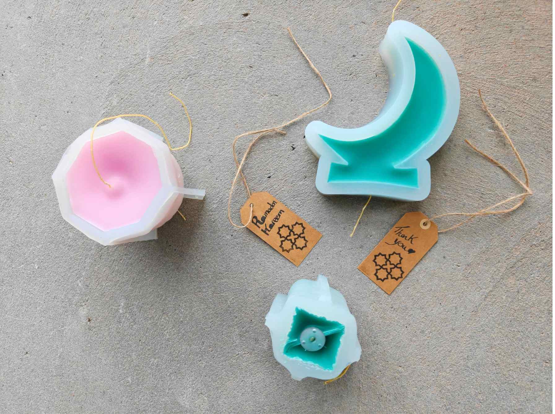 Pastel beeswax Ramadan candles in architectural shapes resting outdoors to cure before lighting.