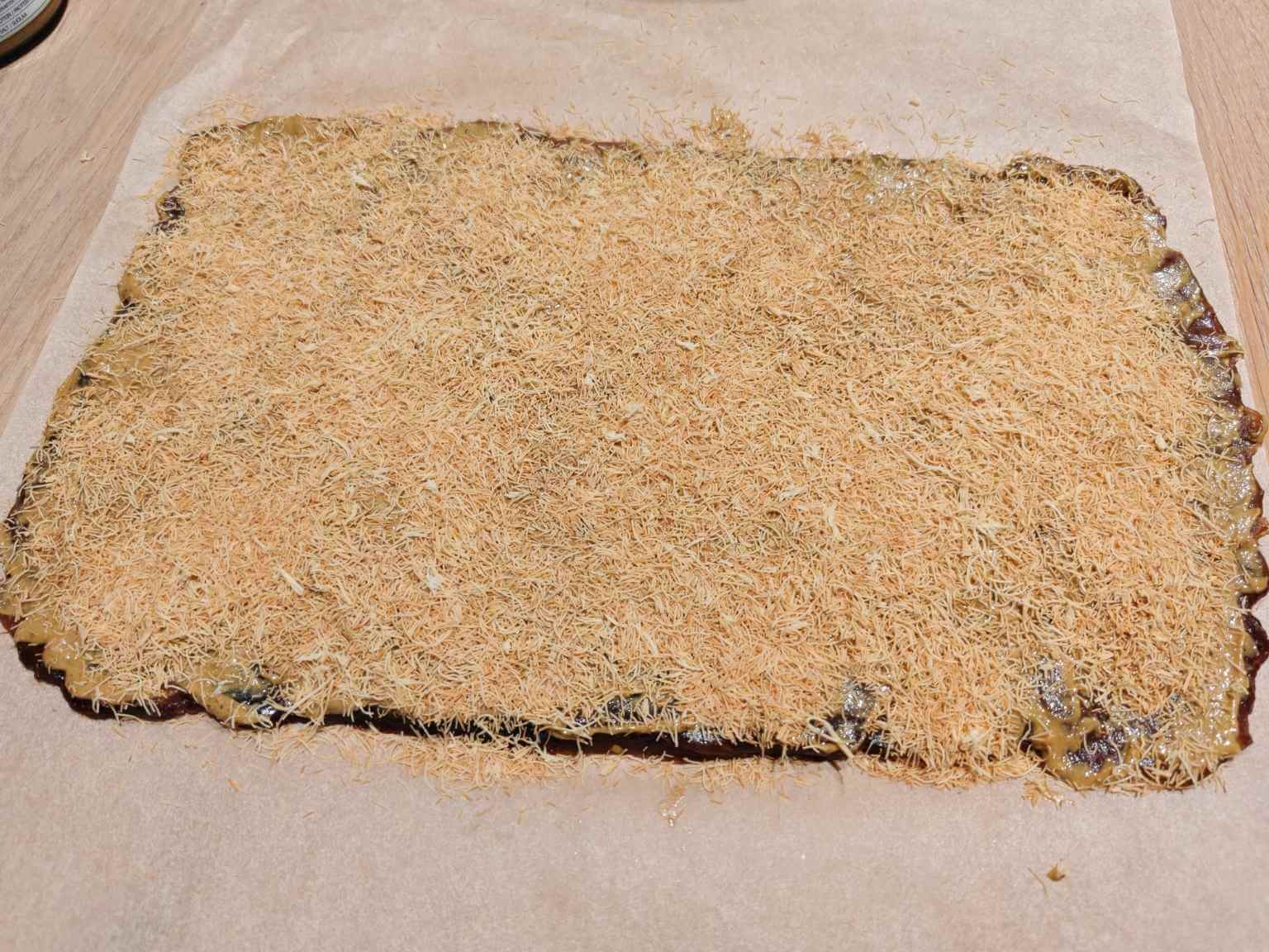 kataifi pastry sprinkled over pistachio date dessert mixture