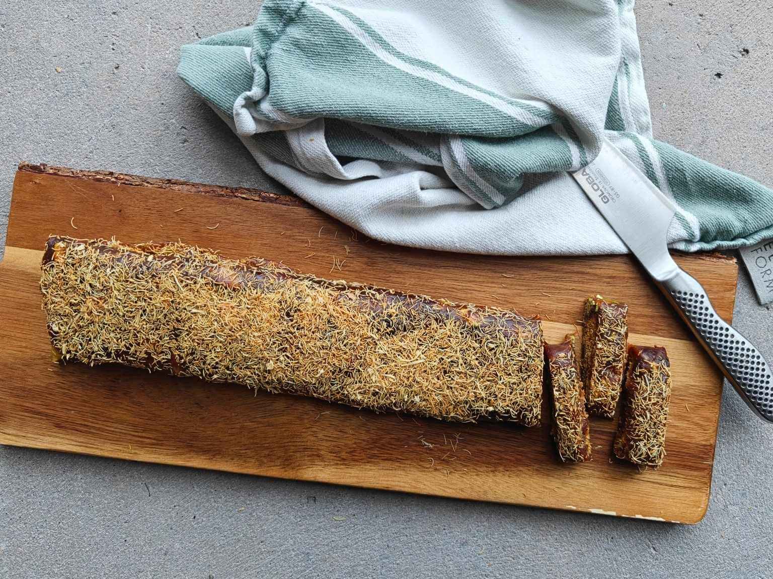no-bake pistachio kataifi date dessert log sliced on a wooden board