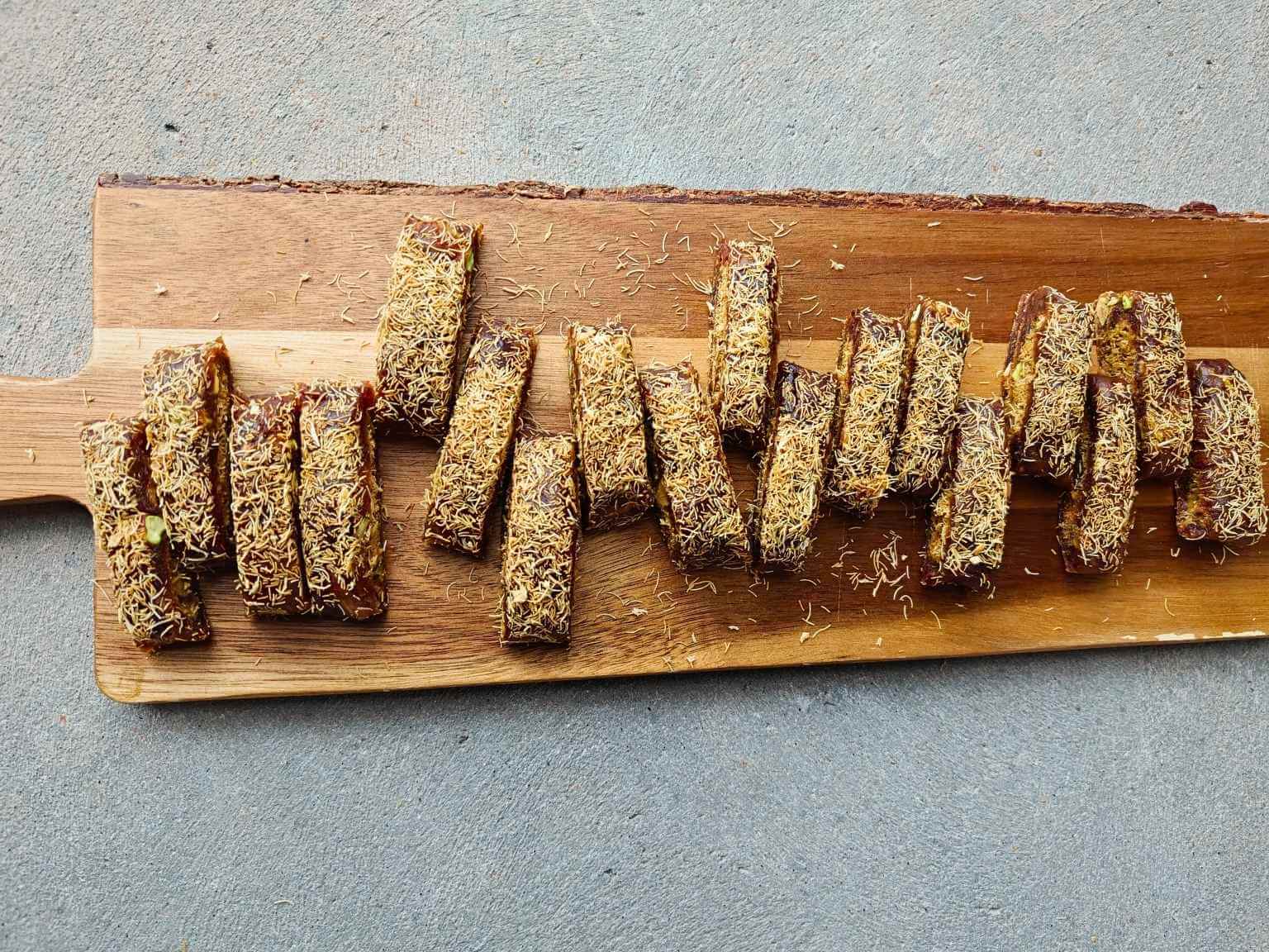 sliced no-bake pistachio kataifi date dessert arranged on a wooden board