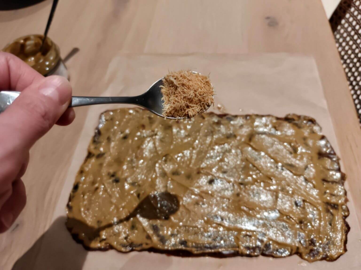 sprinkling kataifi pastry over pistachio date dessert mixture