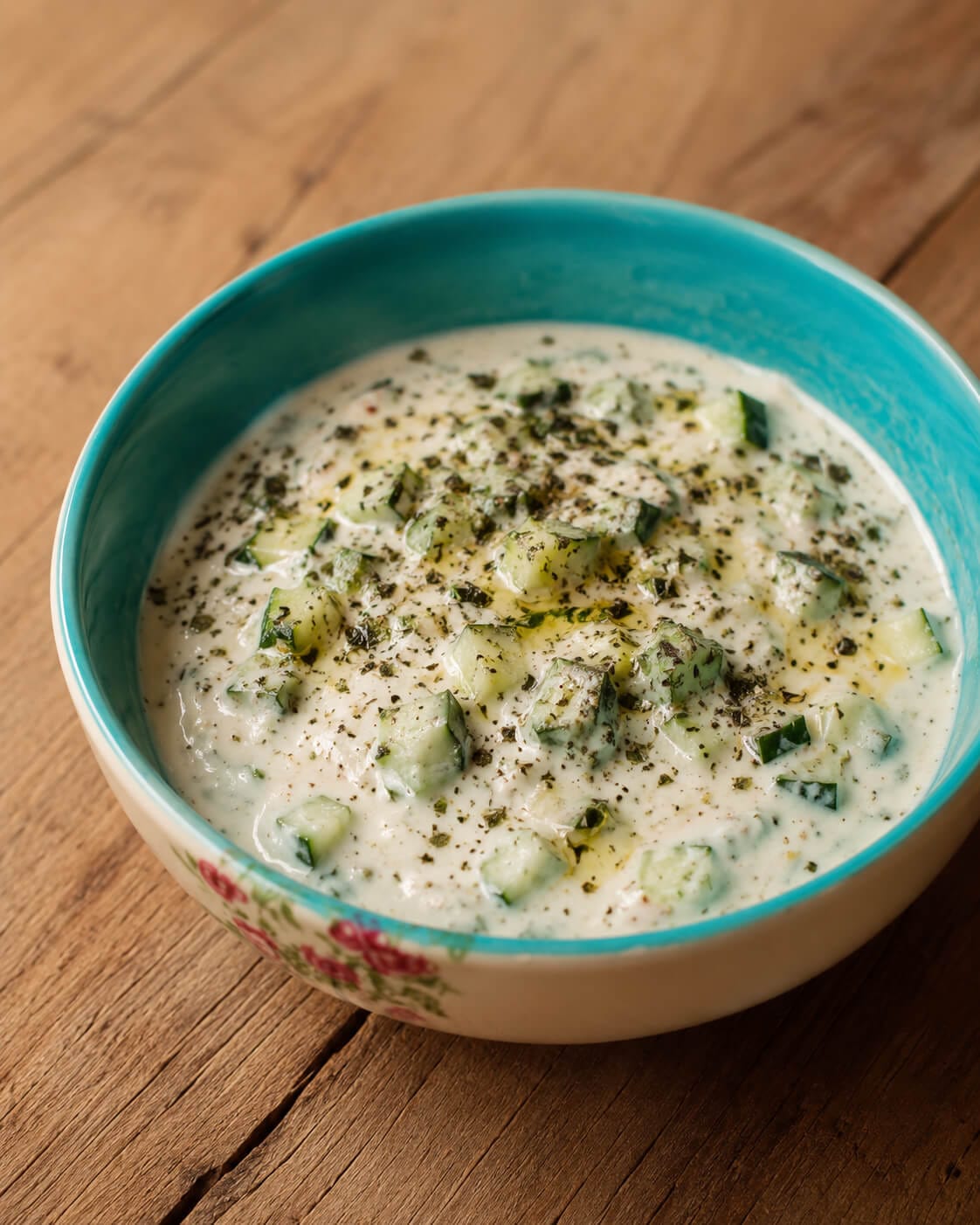 Mast o khiar Persian yogurt and cucumber dip topped with mint, olive oil, black pepper, and chopped cucumber.