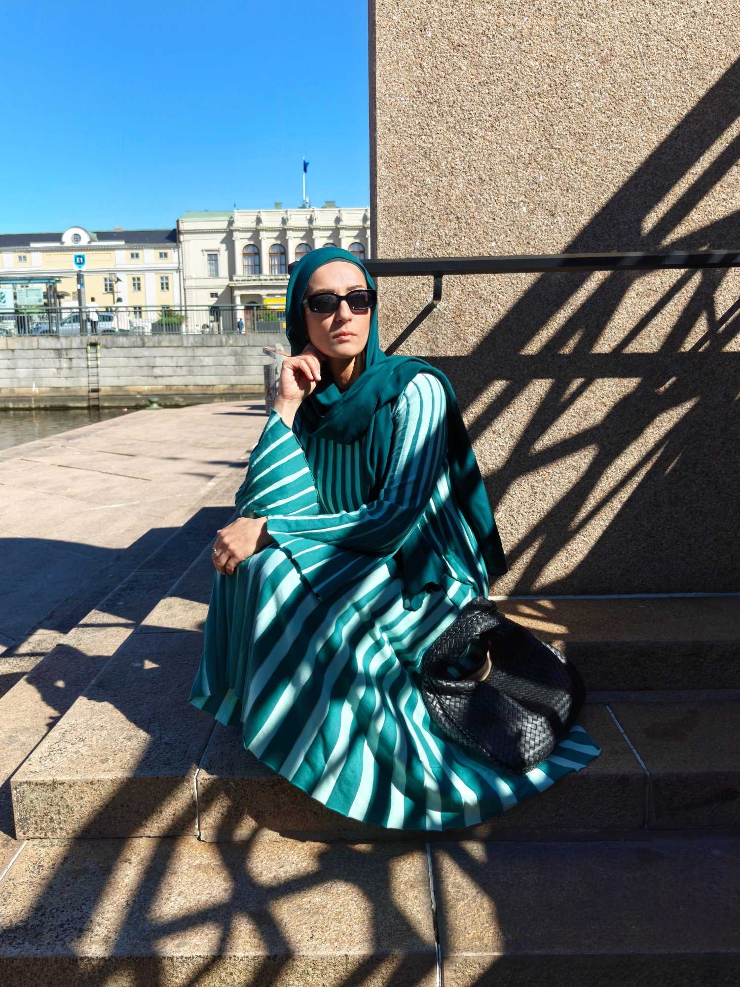 Hijabi woman wearing a green pleated two-piece skirt set from Indiska styled as a modest city outfit