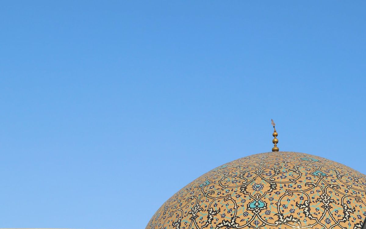 The patterned golden dome of Sheikh Lotfollah Mosque set against a clear blue sky.