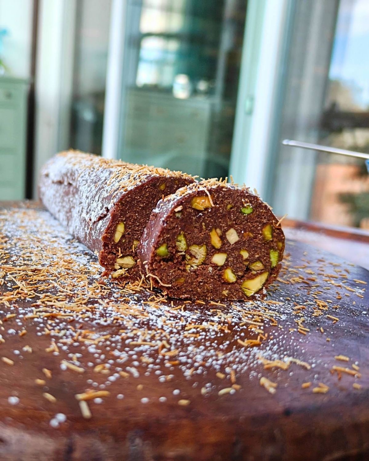 Chocolate kataifi salami sliced, showing pistachios and toasted kataifi strands inside