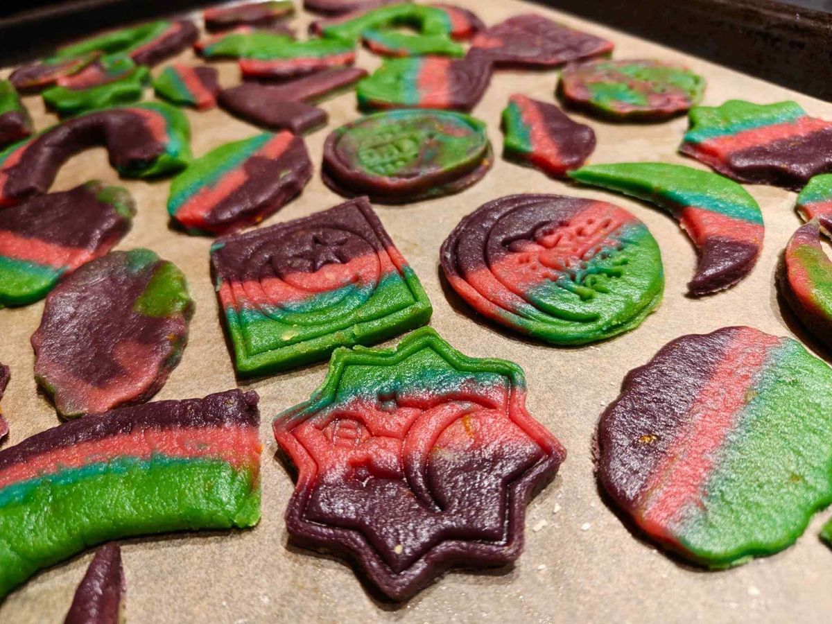 Rainbow-coloured Ramadan cookie shapes arranged on a baking tray before baking